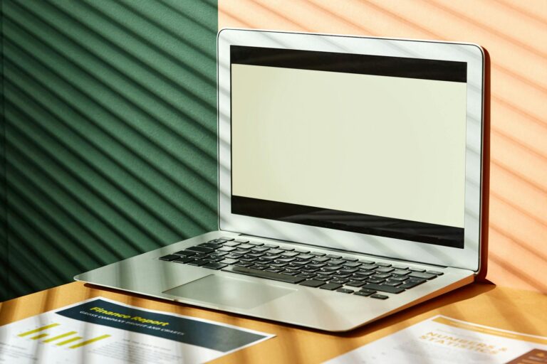 A sleek laptop on a desk with light and shadow play, ideal for tech and business themes.