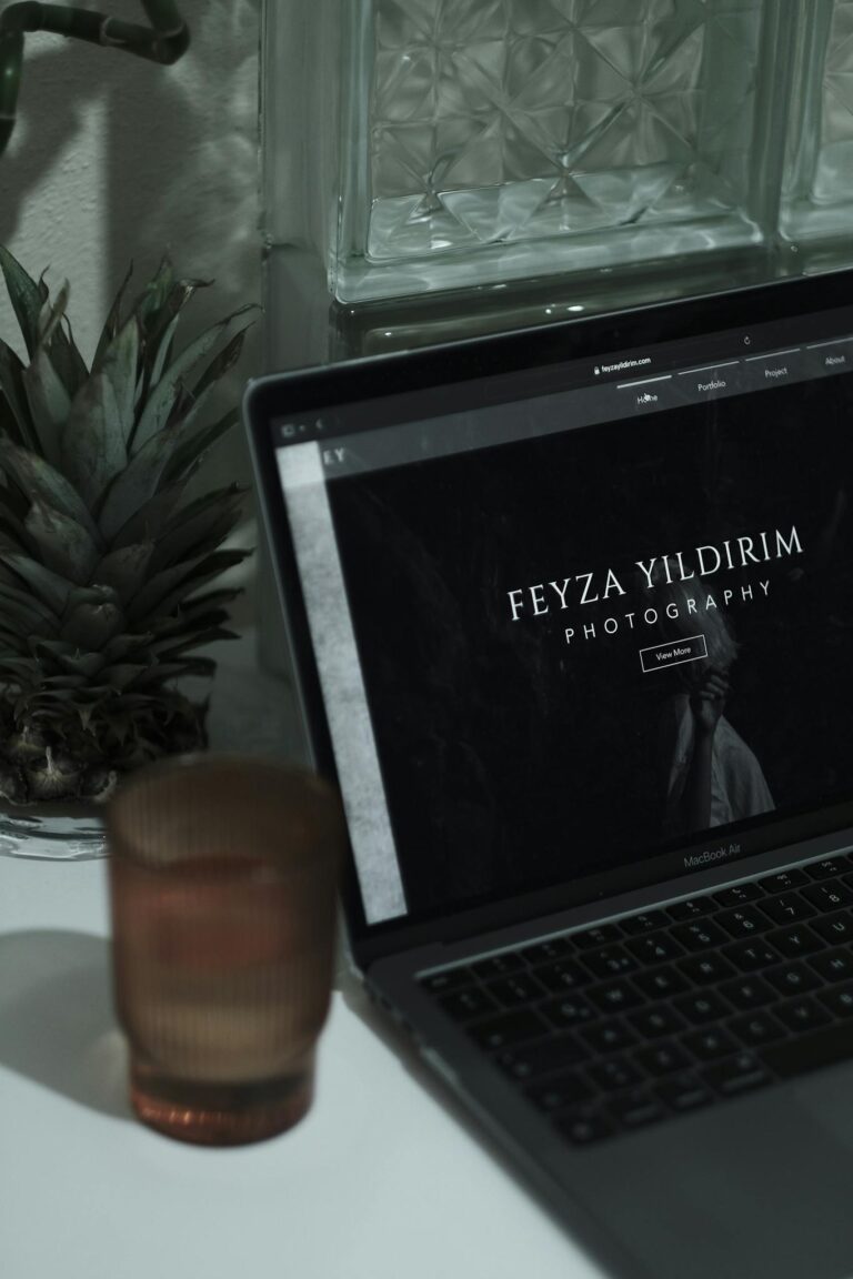 An aesthetically pleasing workspace featuring a laptop with a photographer's website, surrounded by minimalist decor.